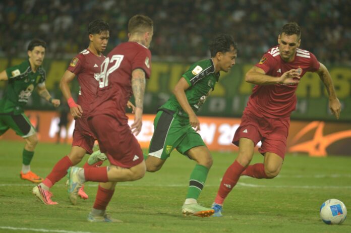 Tiga pemain Persija Jakarta melakukan pengawalan ketat terhadap satu pemain Persebaya Surabaya di Stadion Gelora Bung Tomo.