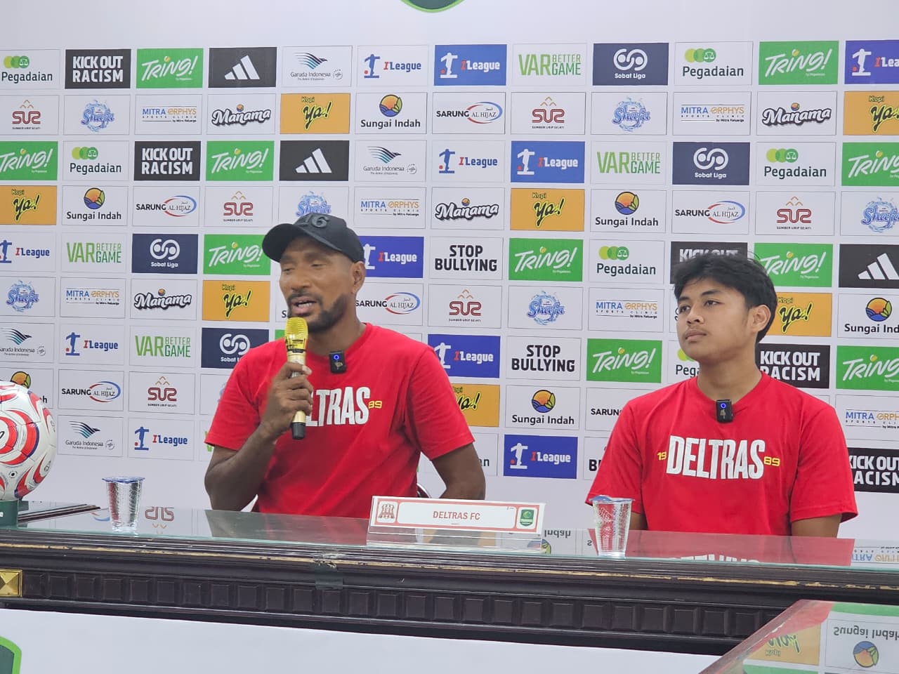 Pemain Deltras FC, Christian Deo Putra Lambok, mendampingi pelatih Leonard Tupamahu dalam sesi jumpa pers.